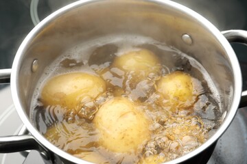Young potatoes boiling in pot on stove, closeup