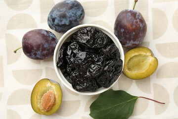 Dried prunes, fresh plums and green leaf on table, flat lay