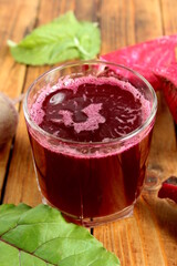There is a glass of freshly squeezed beetroot juice on the wooden table.