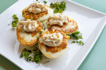 French high cuisine starter dish, pan fried chicken eggs with special filling and yellow sauce, vegetarian food in French restaurant