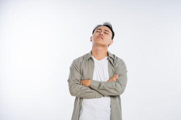 A young man exuding confidence with crossed arms, standing against a blank backdrop.