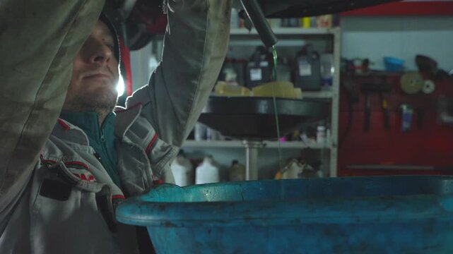 Auto mechanic drains antifreeze from car. Car repair. Replacing coolant in car.