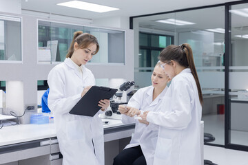 Fototapeta premium Three scientists in lab coats engage in discussion in laboratory