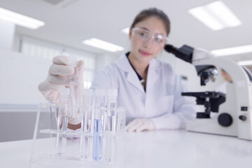 Laboratory technician conducts experiments with test tubes and microscope in a modern research facility