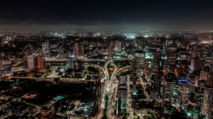 Drone night aerial view of illuminated São Paulo skyline with modern skyscrapers, highways, Octávio Frias de Oliveira cable-stayed bridge and urban lights in Brazil