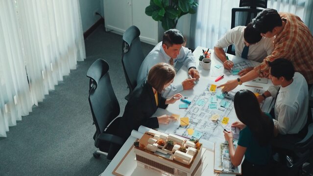 Group of diverse team planning strategy while sitting at table with project plan. Top aerial view of smart business people working together to brainstorm and design house construction. Alimentation.