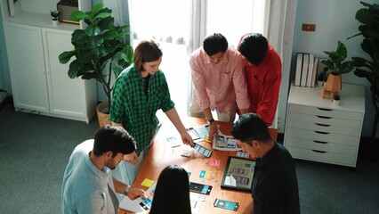 Top view of caucasian developer group planning for digital wireframe design. Skilled diverse designer in casual outfits brainstorming or working together to design mobile app interface. Convocation.