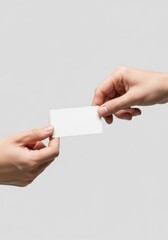 Obraz premium Close-up of two hands exchanging a blank white business card, a professional networking and introduction concept on a clean background