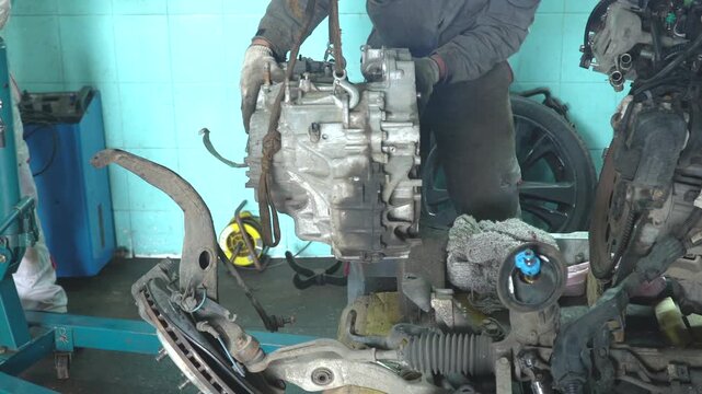 Auto mechanic removes gearbox. Car repair in auto service.