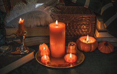 Orange candle on a vintage table, dark academia aesthetic. Evening October time