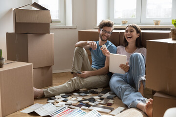 Inspired young married couple resting from unpacking boxes planning renovation