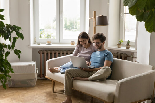 Relaxed young family couple using notebook in cozy living room - Powered by Adobe
