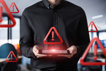 Warning symbols hover around a person using a tablet.