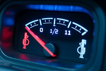 Close up of a car s glowing fuel gauge needle pointing towards empty indicating a need for refueling