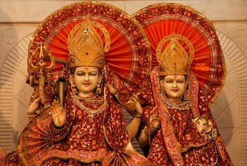 Fototapeta premium Traditional Indian Sculptures Depicting Divine Figures Lord Shiva and Parvati with Ornamented Red Attire and Headdresses