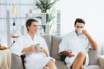 Obraz premium Beauty or body treatment spa salon vacation lifestyle concept with couple wearing bathrobe relaxing with drinks in luxurious hotel spa or resort room. Vacation and leisure relaxation. Quiescent