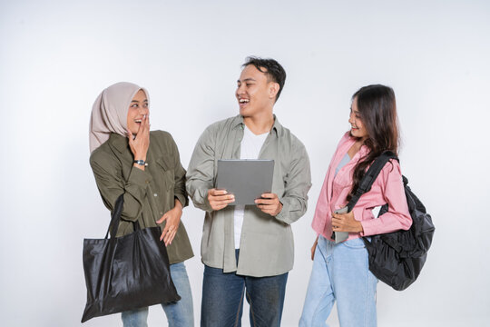 A lively group of friends are joyfully interacting while happily looking at a tablet together