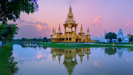 Golden temple at wat rong khun in Chiang Rai, Thailand reflecting in tranquil water during sunset