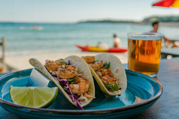 Two grilled shrimp tacos with lime and beer on a blue plate by the sea seafood tortilla