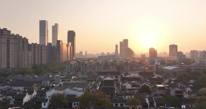 Sunrise over a cityscape with modern high-rises and traditional low-rise dwellings interwoven