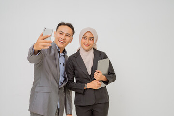Two smiling business professionals happily capture a joyful selfie together during their workday