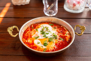 hot fresh shakshuka with garlic and herbs in a small frying pan
