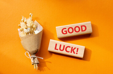 Good luck symbol. Wooden blocks with words Good luck. Beautiful orange background with bouquet of flowers. Business and Good luck concept. Copy space.