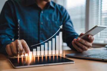Man analyzing financial growth chart on tablet with smartphone and laptop business finance