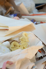 Pile of discarded paper and construction foam waste inside a trash container.
