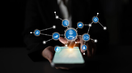 A businessman engages with a smartphone displaying CRM technology icons, symbolizing connectivity, data management, and innovative solutions in the digital landscape. Tessel
