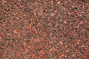 Rubber mulch imitating wood chips, shavings, fractions 12-50 mm. red brown Rubber Playground Surfacing, sports grounds. rubber coating of run track, playground or sports ground texture background.