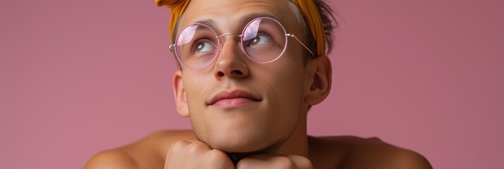 Young caucasian male with glasses and yellow headband against pink background