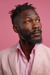Fototapeta premium Confident african male in pink suit against pink background looking upwards