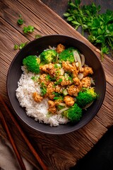 Tender chicken pieces stir-fried with vibrant broccoli and onions atop fluffy white rice create a comforting dish. This flavorful meal is presented in a rustic bowl, garnished with green onions