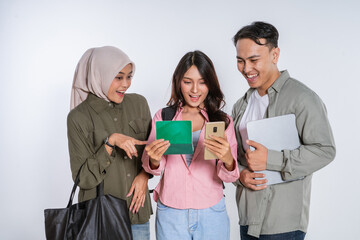 Three friends are happily interacting and engaging with various gadgets in a friendly setting