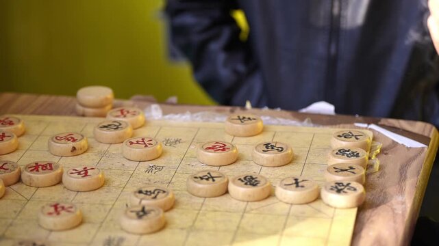 Chinese chess game in progress on a wooden board with carved circular pieces