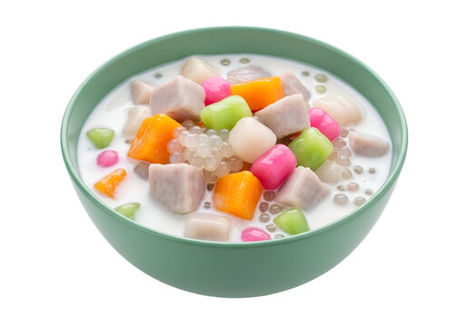 A vibrant assortment of colorful sweet treats, including tapioca cubes, mango pieces, and sweet tapioca pearls, are suspended in a creamy milk-based soup in a light sage-green bowl.