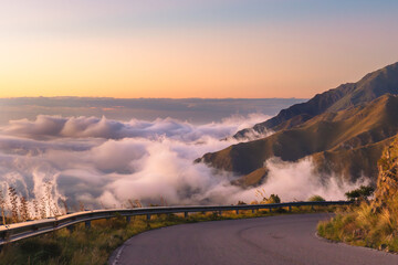 Fototapeta premium Wonderful panoramic view of a mountain road above the clouds in a natural landscape at sunset.