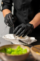 Chef in black gloves plating mashed potatoes in a gourmet kitchen. Professional food preparation with focus on hygiene, precision, and elegant presentation.