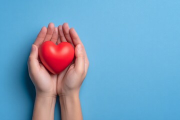Fototapeta premium Symbolic Heart Held by Hands on Blue Background for Marketing Visuals