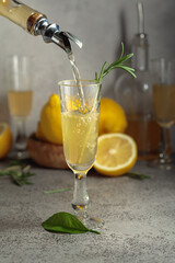 Italian liqueur Limoncello with fresh lemons and rosemary branches.