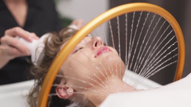 A woman receives hydromassage therapy in a tranquil spa setting, with water gently flowing down her neck, promoting relaxation and rejuvenation through innovative aqua massage techniques.