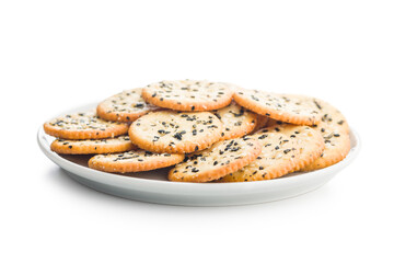 Crispy round salted crackers with sesame seeds on plate isolated on white background.
