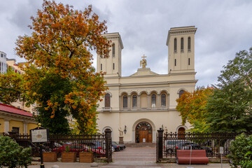 Fototapeta premium Classical Lutheran church facade with ornate cast iron fence and autumn trees in yellow and orange colors. Saint Petersburg, Russia.