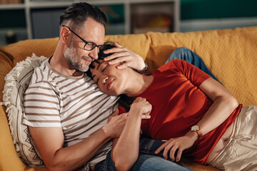 Fototapeta premium Couple relaxing together on sofa, embracing and showing affection
