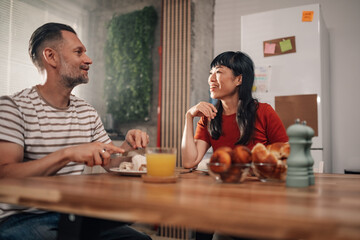 Happy couple enjoying breakfast and conversation at home