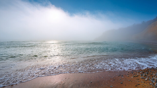 Misty morning ocean sunrise with gentle waves on a pebble beach - Powered by Adobe