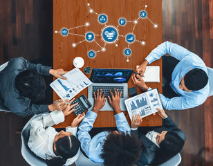A top-view image of a collaborative business meeting featuring diverse professionals analyzing digital data and charts on laptops, fostering strategy and innovation. Amity