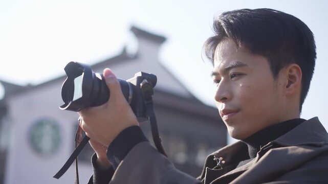 Young man holding camera and focusing intently on street scene photography