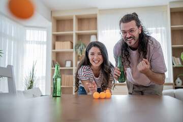Happy couple playing beer pong at home